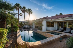 A pool area with lounge chairs, palm trees, and a building with a tiled roof. - Solmirage at PGA West | Nicklaus Fairway Views (La Quinta)