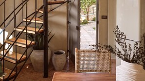 Un escalier en colimaçon avec des marches en bois et des rampes en métal, menant à un espace extérieur offrant une vue sur la verdure.