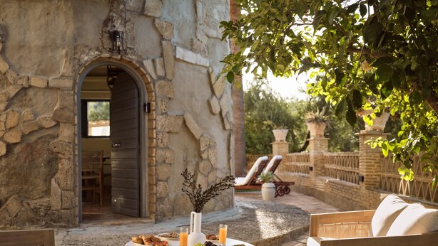 Un bâtiment en pierre avec une porte ouverte donnant sur un patio.