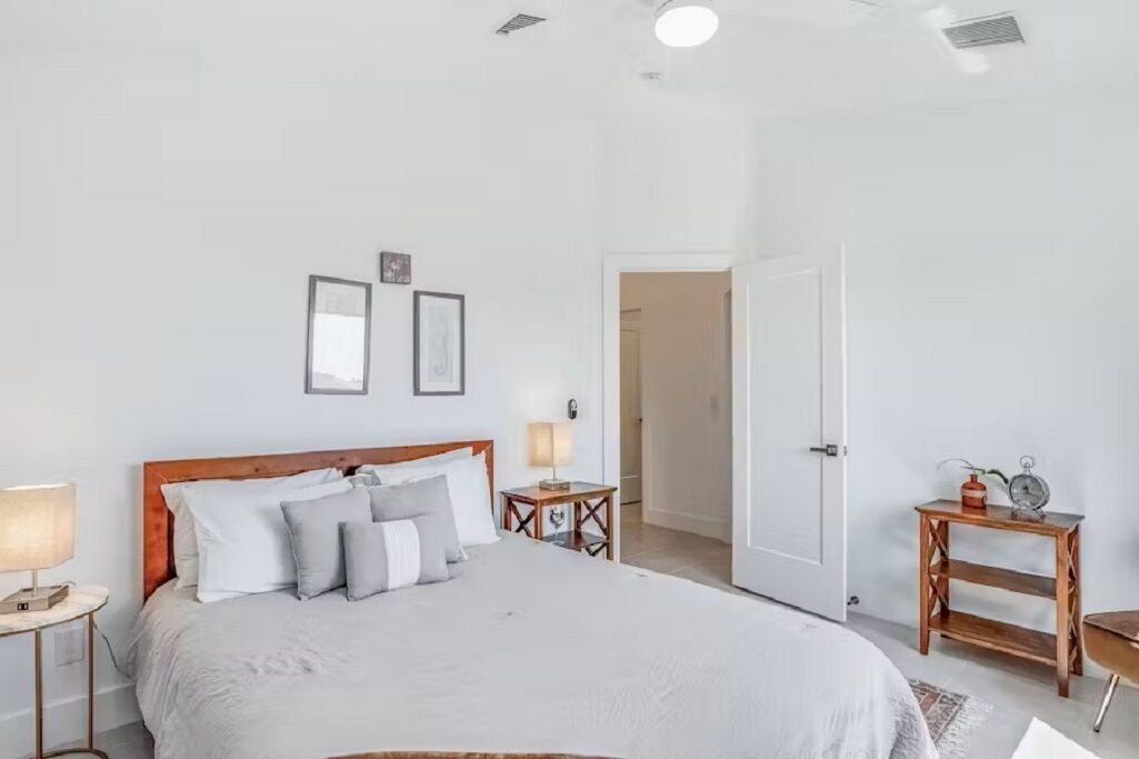 Un dormitorio con cama, mesitas de noche y una puerta.