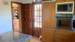 A kitchen with wooden cabinets, a built-in microwave, and an oven. - Villa La Malcontenta, large private house with green spaces and swimming pool. (Alcaucín)