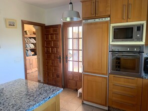 A kitchen with wooden cabinets, a built-in microwave, and an oven.