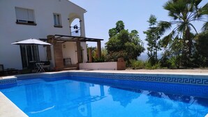 A swimming pool with a geometric tile pattern, a pergola, and a white building with windows and a balcony. - Villa La Malcontenta, large private house with green spaces and swimming pool. (Alcaucín)