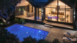 Et moderne hus med swimmingpool, store glasfacader og en terrassemiljø.