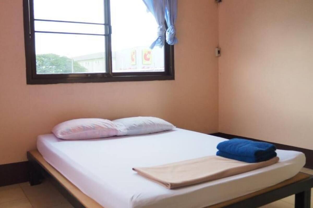 A single bed with a white mattress, two pillows, and a blue towel.