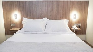 A hotel room with a large bed, wooden headboard, two bedside tables with lamps, and a phone on one of the tables. - Star Inn Hotel Aeroport (Algiers)