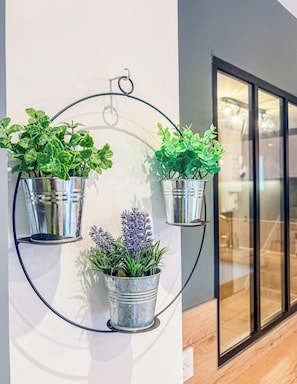 A circular metal stand holding three potted plants against a wall. - Séjour plage & détente – Grand jardin (Guidel)