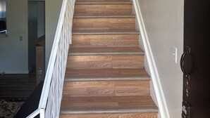 Una escalera con escalones de madera y barandillas blancas que conduce a una plataforma.