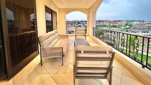 Un balcón con sofá, sillas y una mesa, con vistas a un paisaje urbano.