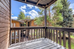 A wooden deck with a view of a cabin and surrounding trees. - 434 Gore Creek Dr-All Seasons D3-Vail Village, Pets, Short Distance to Gondola  & Golden Peak (Vail)