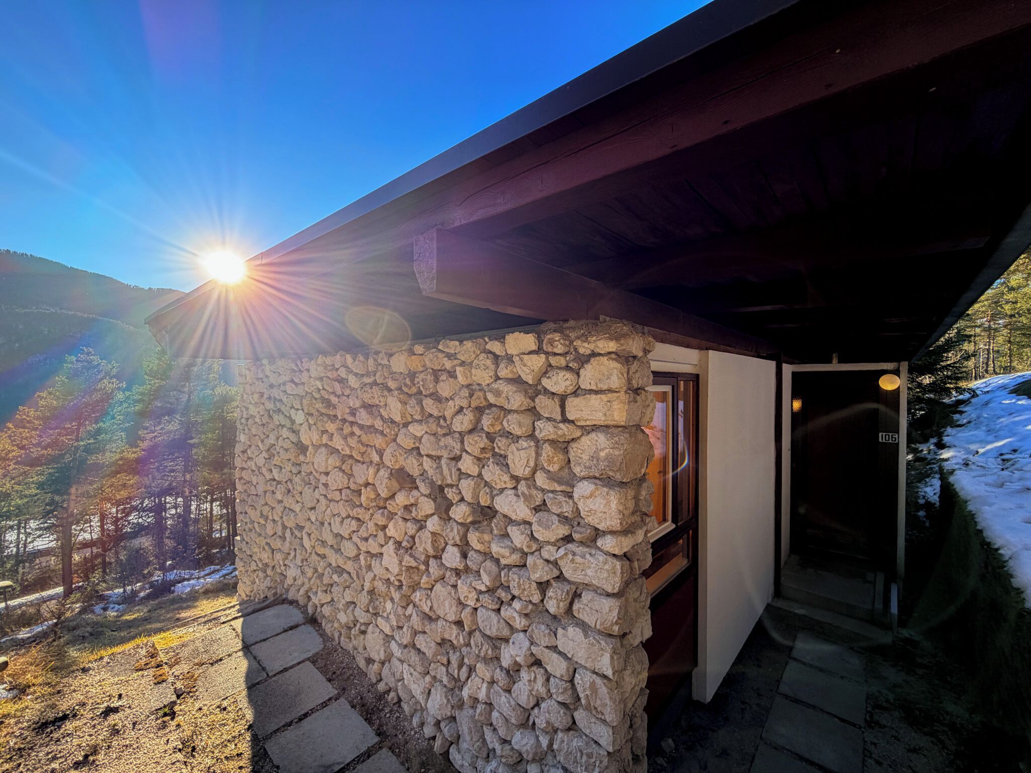 A stone building with a wooden door labeled "106" and a stone wall.