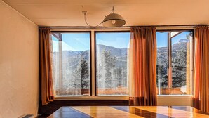 A room with a large wooden table, a bench, and a view of a mountainous landscape through large windows with curtains. - Panoramic Chalet in the ENI Village near Cortina D'Ampezzo - Spa - Restaurant (Corte)
