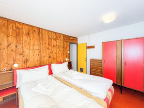 A double bed with white linens, a wooden headboard, a bedside table with a lamp, a wooden wardrobe, and a yellow door. - Panoramic Chalet in the ENI Village near Cortina D'Ampezzo - Spa - Restaurant (Corte)