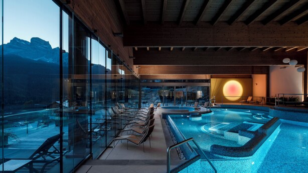 A modern indoor swimming pool with glass walls, wooden beams, and a view of mountains. - Panoramic Chalet in the ENI Village near Cortina D'Ampezzo - Spa - Restaurant (Corte)