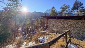 A stone wall with a wooden bench, surrounded by trees and a mountain backdrop. - Panoramic Chalet in the ENI Village near Cortina D'Ampezzo - Spa - Restaurant (Corte)