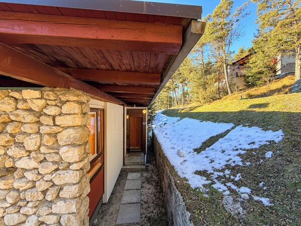 A stone building with a wooden porch and a stone wall.
