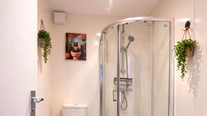 A modern bathroom with a glass shower enclosure, a toilet, and a colorful striped rug. - Brighton Colour Pop House-Sleeps up to 12 (Brighton and Hove)