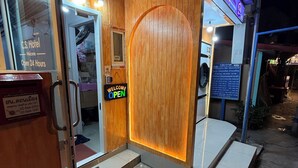 Een hotelentree met een houten deur, een welkomstbord en een neonreclame erboven.