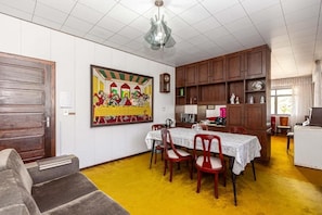 A dining area with a table set for four, wooden cabinets, a clock, and a colorful painting on the wall.