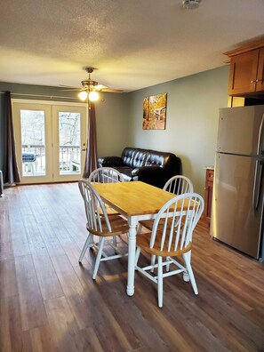 A dining area with a wooden table and white chairs, a black leather couch, and a stainless steel refrigerator. - 2 Bedroom - 1 Bath Lakefront (Climax Springs)