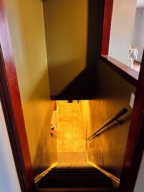Een trap met een leuning, beklede treden en een houten balustrade.