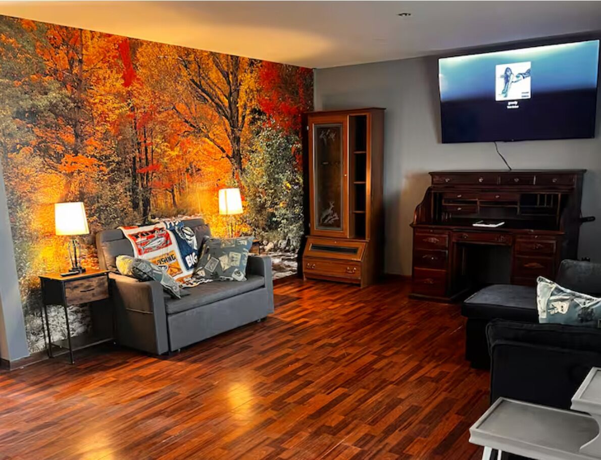 A living room with a large painting, a flat-screen TV, a wooden cabinet, and a sofa.