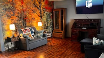 Un salon avec un grand tableau, un téléviseur à écran plat, un meuble en bois et un canapé.