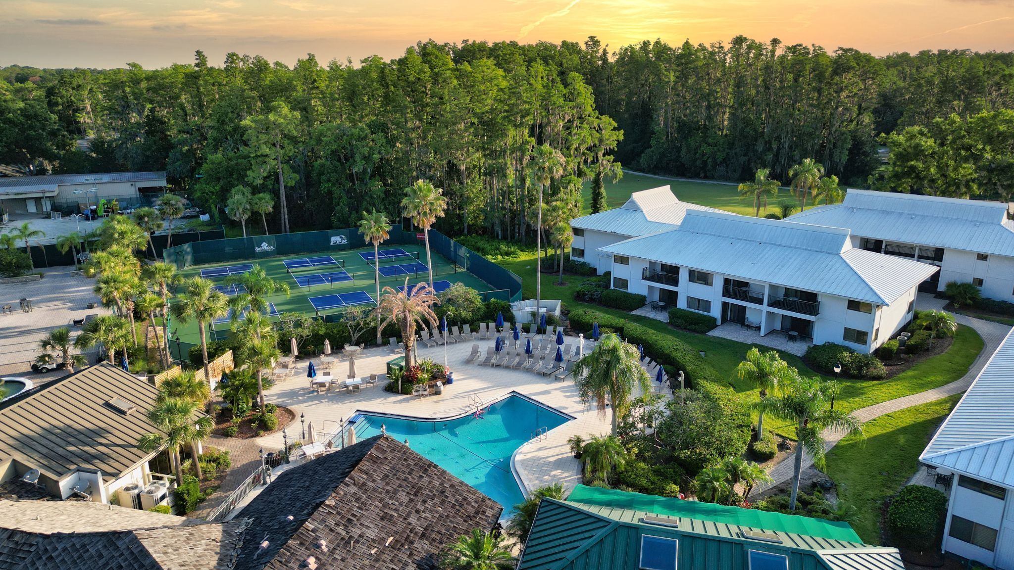 Un resort con cancha de tenis, piscina y habitaciones para huéspedes.