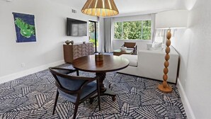 A modern living room with a round dining table, a sofa, and a large window.