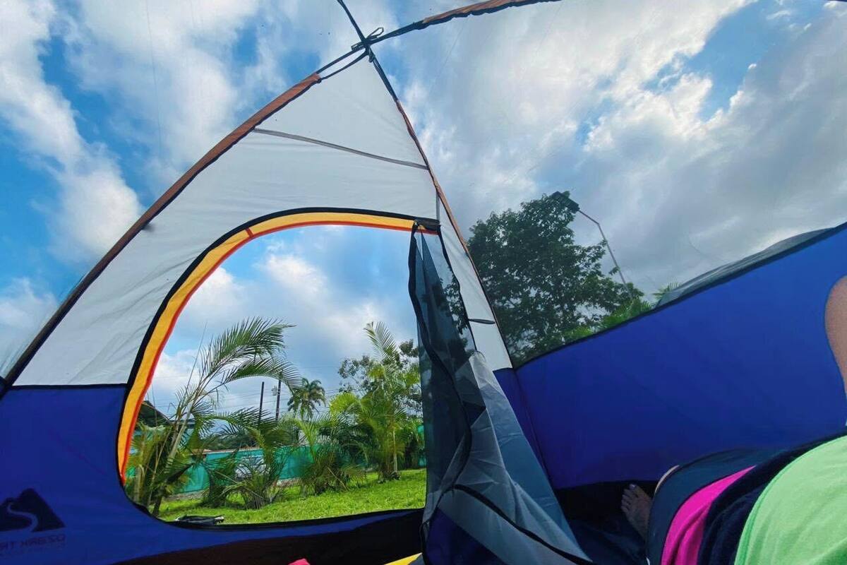 A tent with a clear view of the surrounding greenery and a partly cloudy sky.