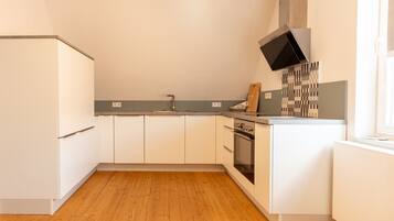 Eine moderne Küche mit weißen Schränken, Holzboden und einem eingebauten Backofen.