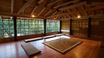A traditional room with tatami mats, wooden beams, and large windows.