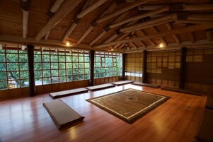 A traditional room with tatami mats, wooden beams, and large windows.