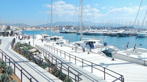 Un port de plaisance avec des bateaux amarrés, une promenade bordée d’escaliers et une vue sur la ville en arrière-plan.