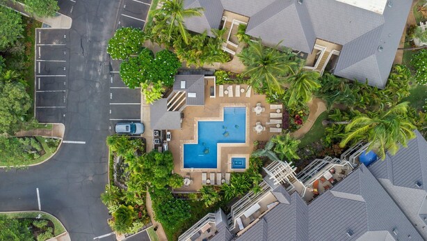 An aerial view of a resort with a swimming pool, lounge areas, and lush landscaping. - Grand Champions Villas in Wailea, Maui (Kihei)