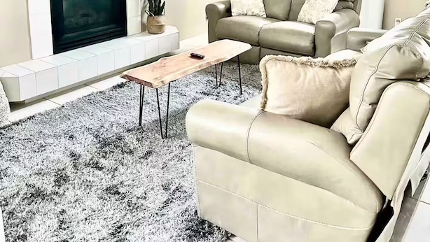 Un soggiorno con camino, un divano, una TV e un lampadario.