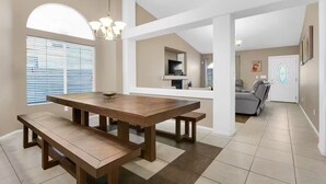 Un'ampia zona giorno con un grande tavolo da pranzo in legno, un divano confortevole e un moderno lampadario.