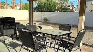 Una terrazza esterna con barbecue, sedie e tavolo.