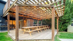 Une terrasse en bois avec une table de pique-nique et des guirlandes lumineuses.