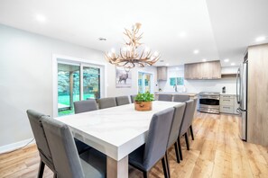 A modern kitchen with a large island, stainless steel appliances, and a chandelier.