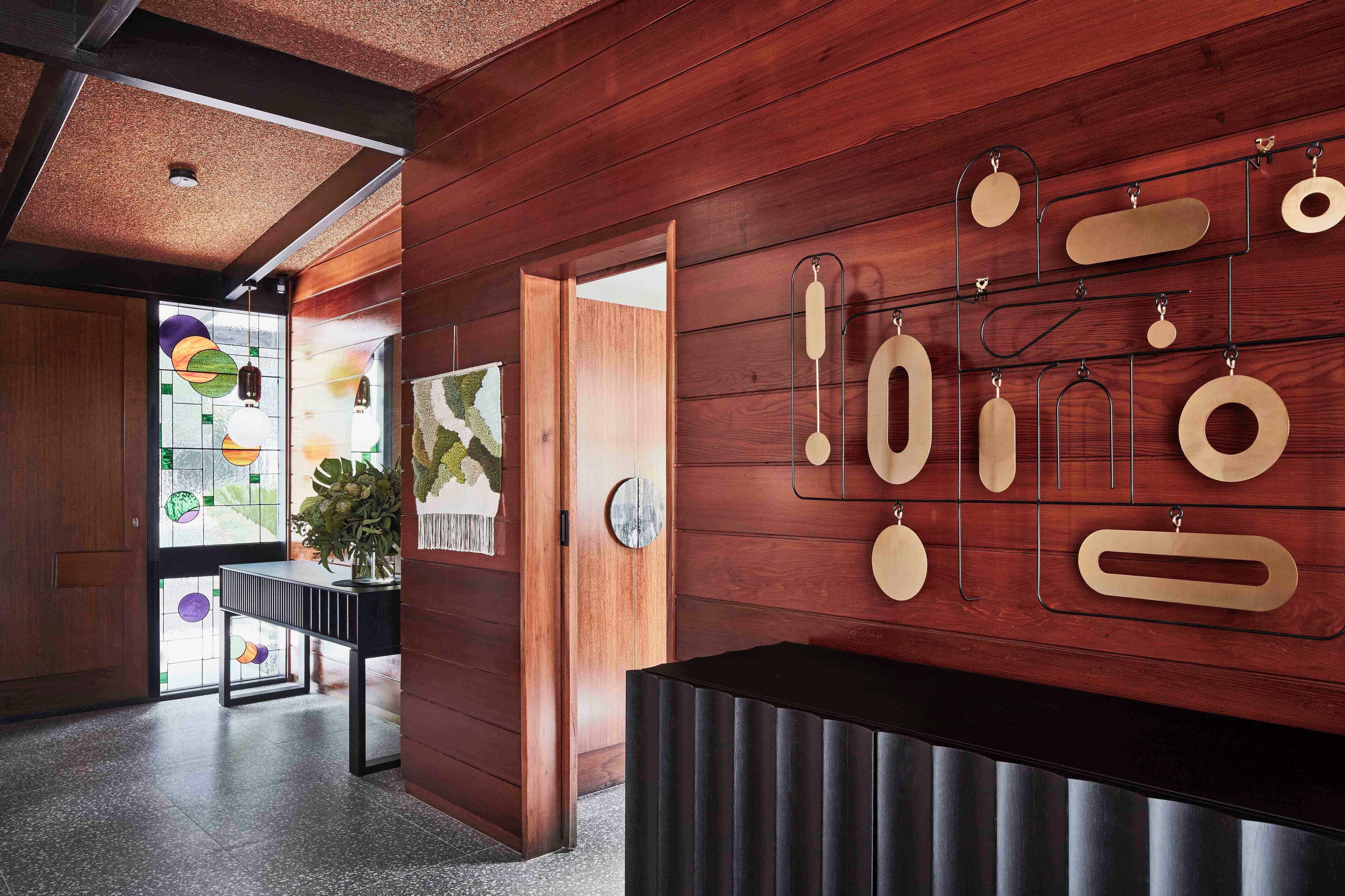 A modern interior with wooden panel walls, a black reception desk, and a wall-mounted display of various shapes.