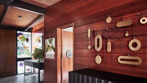 Un interior moderno con paneles de madera, una recepción negra y una pantalla mural con varias formas.