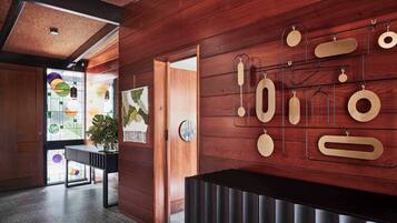 A modern interior with wooden panel walls, a black reception desk, and a wall-mounted display of various shapes.