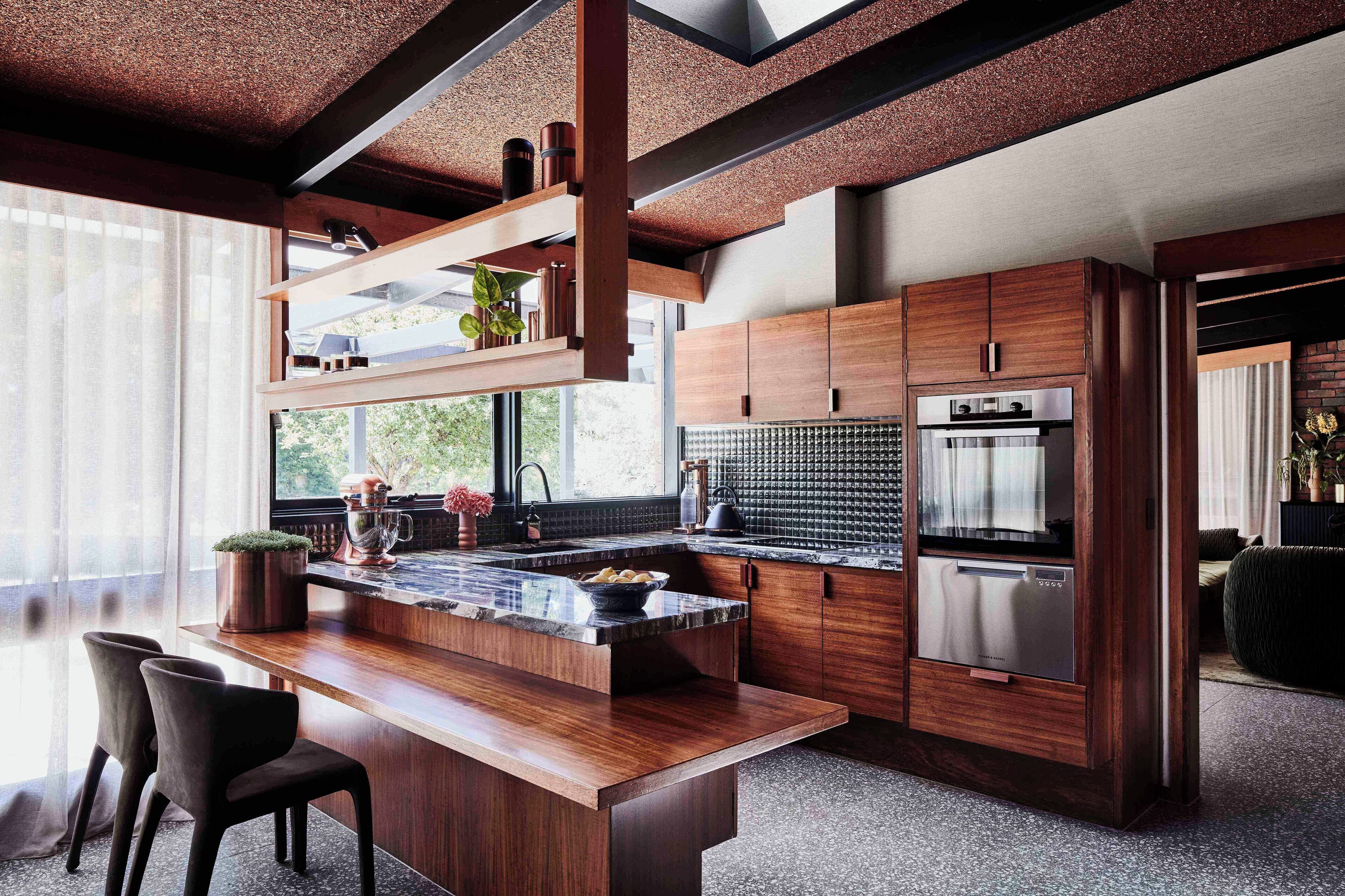 A modern kitchen with wooden cabinetry, a marble countertop, and stainless steel appliances.
