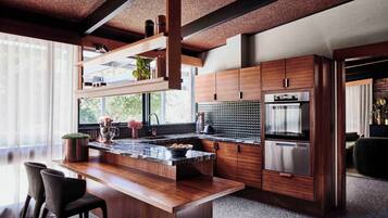 A modern kitchen with wooden cabinetry, a marble countertop, and stainless steel appliances.