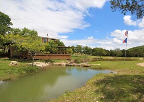 A pond with a wooden deck and a house in the background.