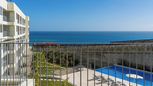 Ein Balkon mit Pool, Meerblick und ein Gebäude mit mehreren Balkonen.