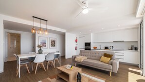 Ein modernes Wohnzimmer mit Sofa, Couchtisch und Essbereich.