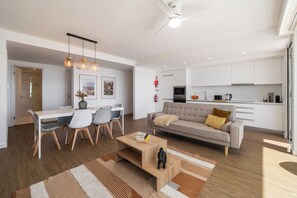 A modern living room with a sofa, coffee table, and dining area.
