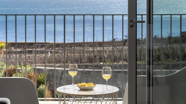 Ein Balkon mit Tisch für zwei Personen, mit Blick auf die Küste.